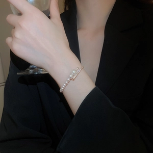 Detail of elegant layered pearl and rhinestone open bracelet on model with black suit