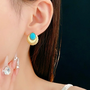 Close-up of vintage gold scallop earring with oval blue stone inlay on a model