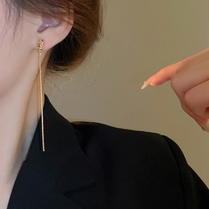 Vue détaillée des boucles d'oreilles dorées à longs glands portées avec un blazer
