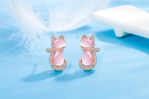 Detailed macro view of rose gold cat stud earrings with pink opal and tiny crystals