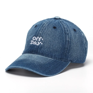 Close-up of white 'Off Day' embroidery on dark blue denim baseball cap with curved brim