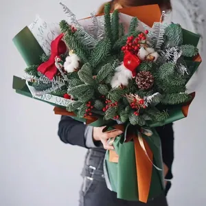 Christmas bouquet with Nobilis fir, red berries and pine cones held by model