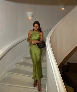 Detail of elegant emerald green satin halter neck maxi dress worn on a spiral staircase