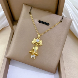 Macro shot of gold bow and bell pendant with sparkling zircons on a luxury necklace