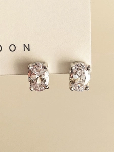 Close-up of oval-cut zircon earrings with four-prong silver setting on display