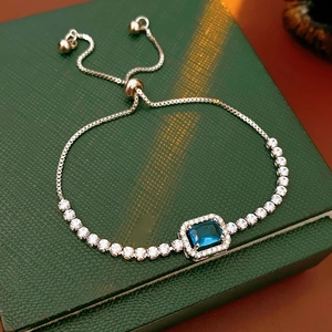 Macro view of adjustable silver bracelet with a rectangular deep blue gemstone and halo stones