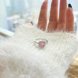 Macro shot of cushion-cut pink gemstone ring with halo diamonds on a silver band