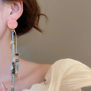 Close-up of bohemian style beaded tassel earrings featuring pink stone and multi-colored beads