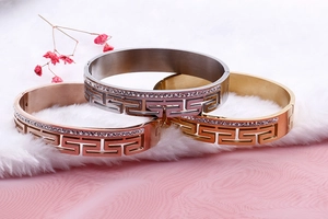 Close-up of stainless steel bangles with Greek key pattern and rhinestone inlays