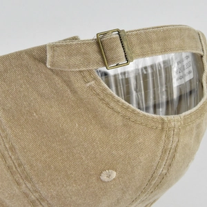 Detail of adjustable brass buckle and corduroy texture on khaki cotton baseball cap