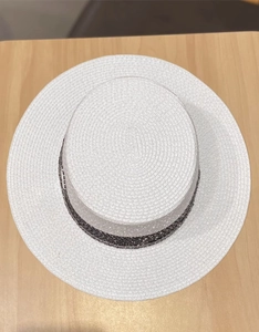 Vista dall'alto di un cappello di paglia bianco con nastro grigio su legno