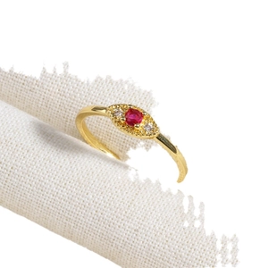 Luxury gold ring with a red gemstone center and white zircon stones in an eye design
