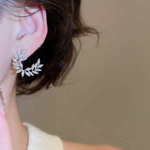 Primo piano di eleganti orecchini a spiga di grano in argento con zirconi su modella