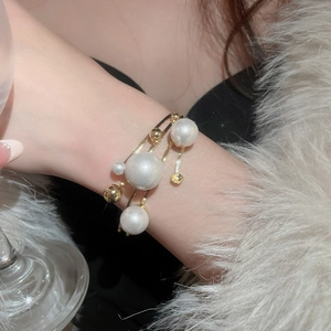 Detail view of a multilayered gold pearl bracelet on a model in a luxury setting