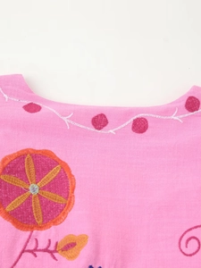 Detailed close-up of colorful floral embroidery on pink cotton linen fabric neckline