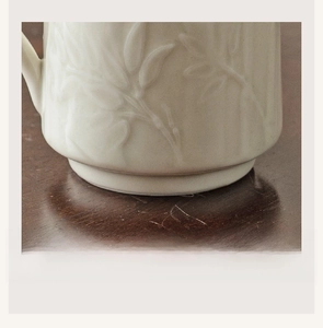 Macro detail of ceramic cup base featuring elegant bamboo leaf relief on smooth porcelain
