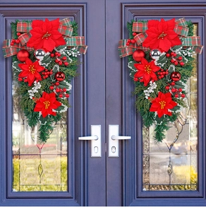 Detail of hanging Christmas swags with poinsettias and berries on dark double doors