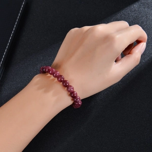 Detail of beaded garnet or agate bracelet worn on wrist over a dark textured backdrop