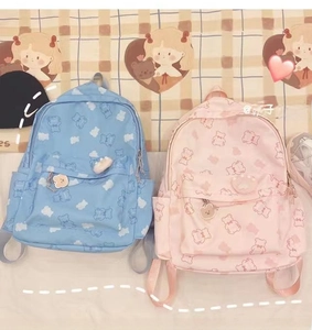 Detail of pink and blue canvas backpacks with cute bear prints and matching pendants