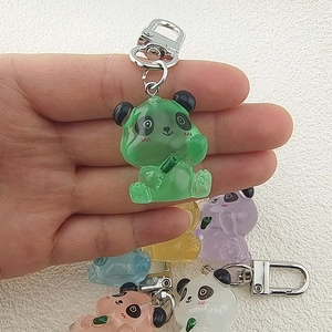 Cute luminous panda keychain in translucent resin with multiple colors shown in the hand