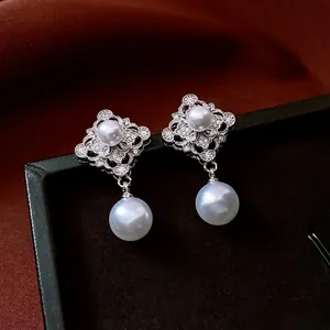 Exquisite pearl drop earrings with zircon clover design on black velvet and red silk