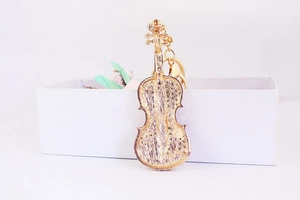 Vue détaillée du dos du porte-clés violon en métal doré avec surface texturée sur boîte