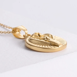 Macro detail of a religious medallion pendant in gold finish with embossed relief