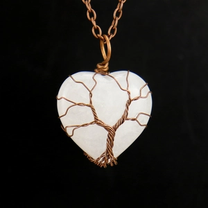 Detailed view of handmade bronze wire-wrapped tree of life on heart opal pendant