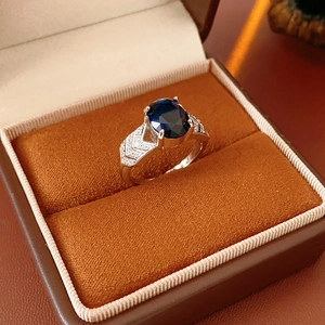 Bague en argent avec une grande pierre bleue ovale et pavage de zircons sur anneau en V