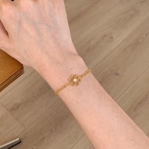 Bracelet doré élégant avec fleur ajourée et perle au poignet pour un style quotidien