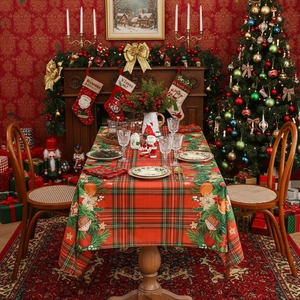 Red Christmas tablecloth with green plaid, poinsettias and pine branches on festive table