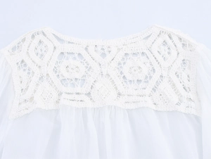 Detail of white crochet lace neckline and pleated chiffon fabric on an elegant blouse