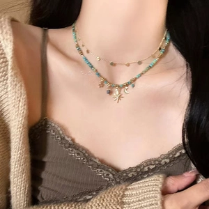 Detail shot of a layered beaded necklace featuring gold star and moon pendants on a model
