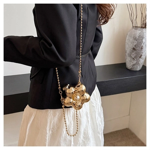 Détail d'un mini sac floral doré avec perle et chaîne porté par un mannequin