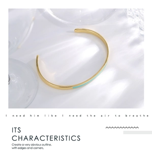 Detailed view of an 18K gold open C-shaped cuff bracelet with light blue enamel inlay