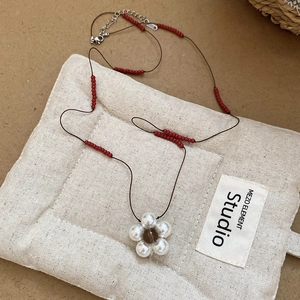 Detail of beaded cord necklace featuring pearl flower pendant and silver lobster clasp closure