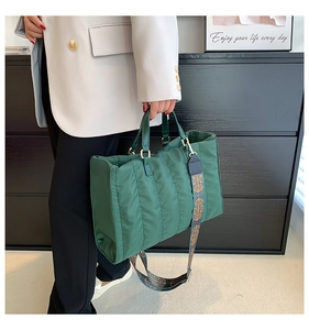 Detail of dark green quilted tote bag featuring a vintage ethnic pattern wide strap