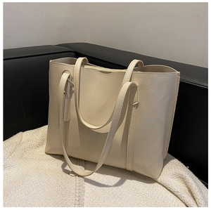 Detail view of large cream leather tote bag resting on a white knitted blanket