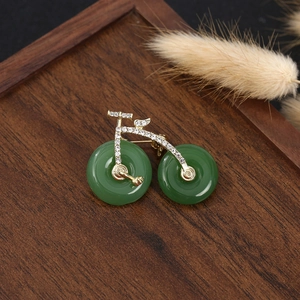 Detail of a vintage golden bicycle brooch with green stone wheels on a wood tray