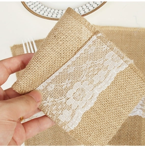 Close-up of burlap cutlery pouch with white floral lace for rustic wedding table decor