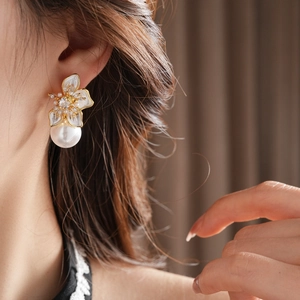 Detail of floral gold plated stud earrings with crystal center and large round pearl