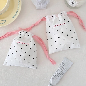 Close-up of polka dot drawstring storage bags with pink woven cords and brand labels