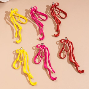 Three pairs of matte ribbon bow earrings in yellow, rose red and red with small rhinestones