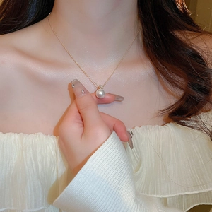 Detail of round pearl pendant with zircon inlay on a delicate gold chain for women