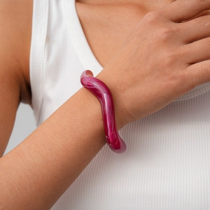 Detail shot of wavy acrylic cuff bracelet in pink marble texture on female wrist