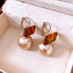 Boucles d'oreilles vintage avec pierres ambrées et perles champagne sur boîte à bijoux