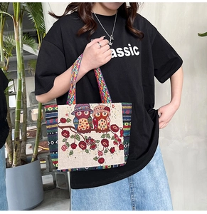 Close-up of ethnic embroidered tote bag with owl floral pattern and colorful woven handle