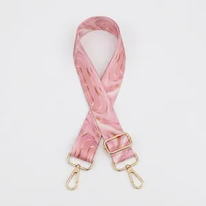 Detail of adjustable bag strap with pink and gold marble pattern and metal lobster clasps