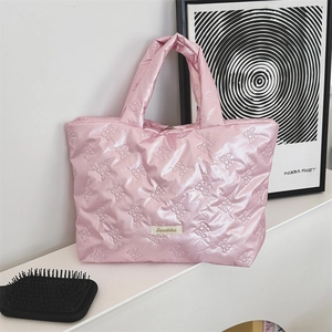 Detailed close-up of pink quilted tote bag with bow patterns and brand label