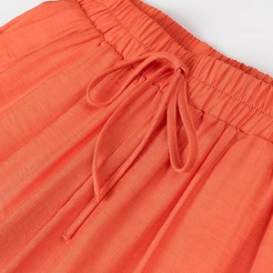 Détail du pantalon plissé orange avec taille élastique et cordon de serrage réglable